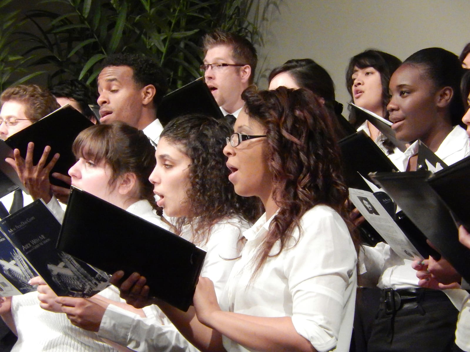 Choir members singing from their music folders