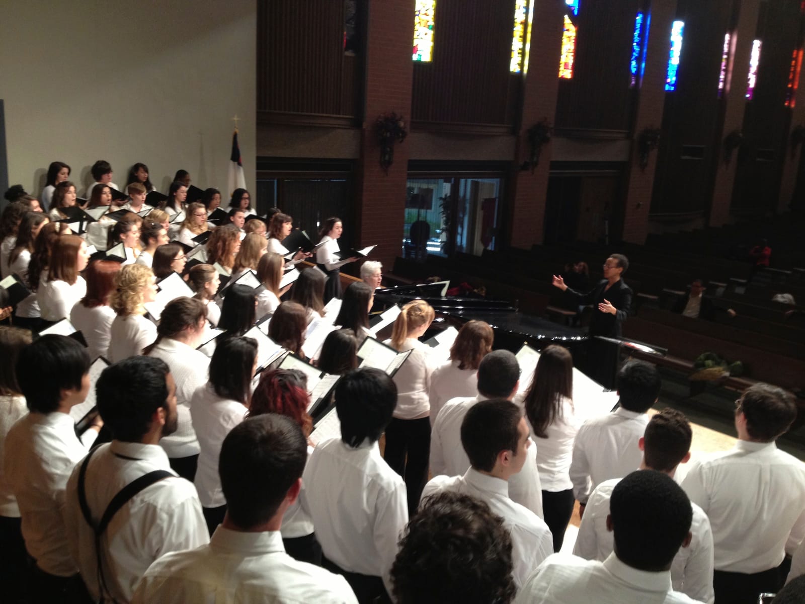 A choir singing in a church, led by a conductor